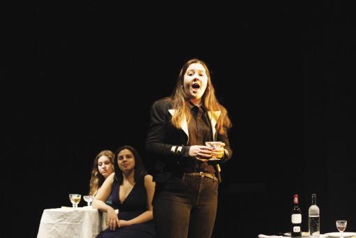 young woman singing on stage with a drink in her hand