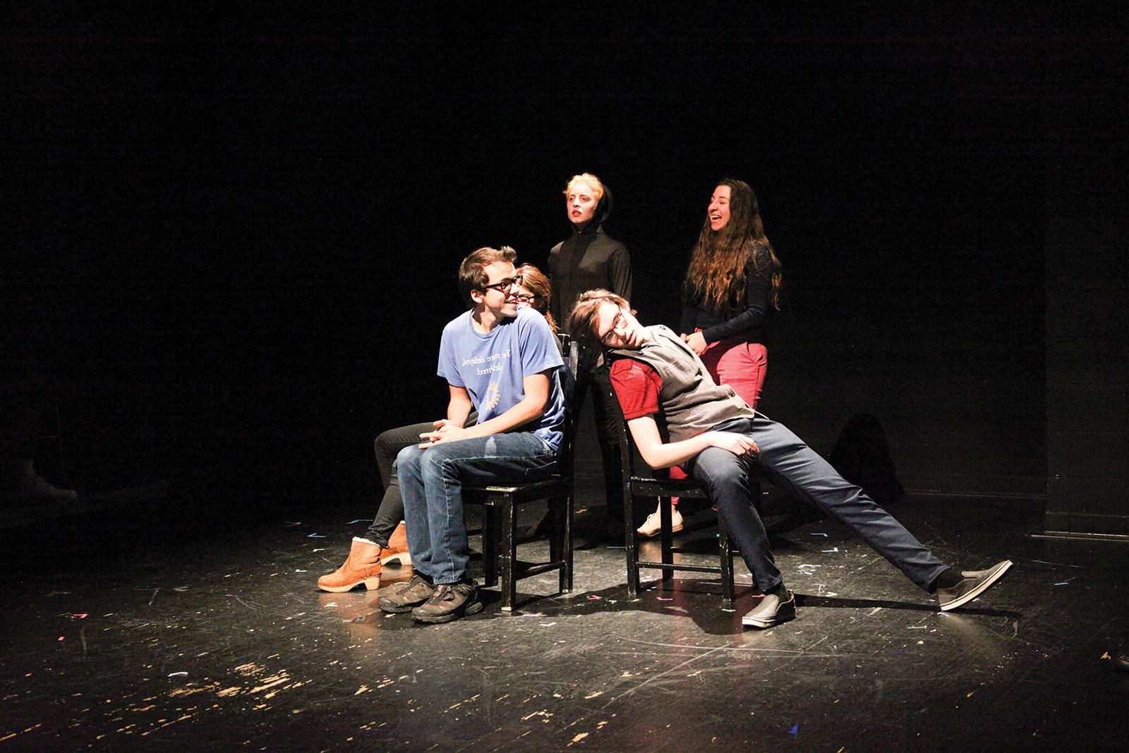 4 students on stage, 2 seated, 2 standing behind
